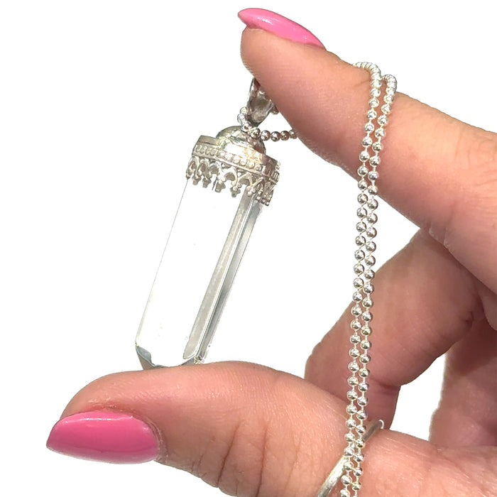 "Handmade Clear Quartz point necklace with sterling silver bezel cap" on white in hand for up close view