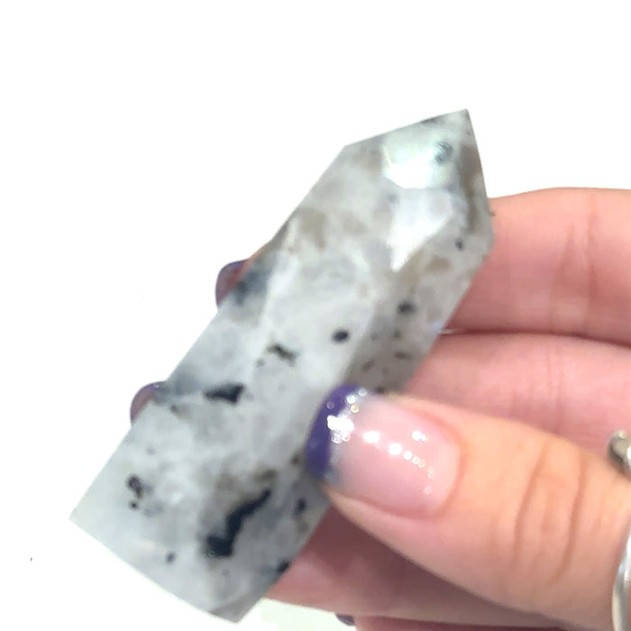Ethically sourced Rainbow Moonstone crystal tower with free information card on white in hand for close up view